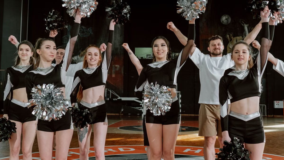 Energetic cheerleading team performing indoors with pompoms and uniforms.